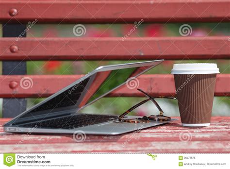 Laptop With Glasses And Notebook Lying On Bench In City Park Outdoor
