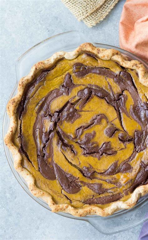 A Pie With Chocolate Swirls On Top In A Glass Pie Plate Next To A