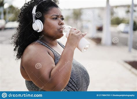 Curvy Woman Drinking While Doing Jogging Routine Outdoor At City Park