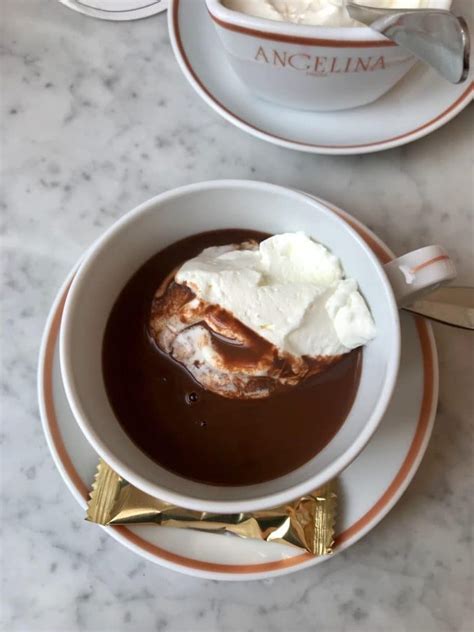 A Bowl Filled With Chocolate And Whipped Cream On Top Of A White Countertop Next To Two Gold