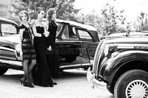 Three Young Girl In Retro Style Dress Near Old Classic Vintage Cars