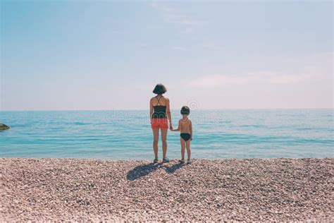 A Boy With His Mother Standing On The Beach And Looking At The Sea