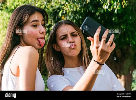 Female Teenager With Pouting Lips Near Best Friend With Acne And Tongue