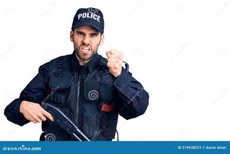 Young Handsome Man With Beard Wearing Police Uniform Holding Shotgun