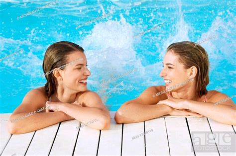 Two Young Women In Pool At Poolside Splashing Feet Front View Stock
