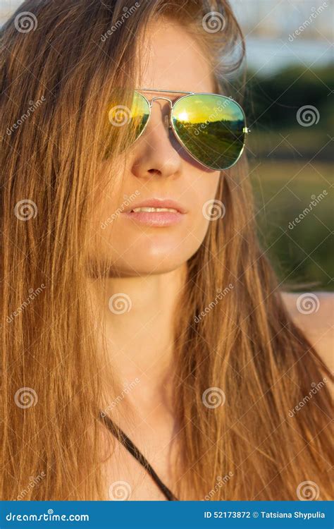 Beautiful Girl With Long Hair With Tanned Skin Wearing Sunglasses On The Beach Of Sunny Warm Day