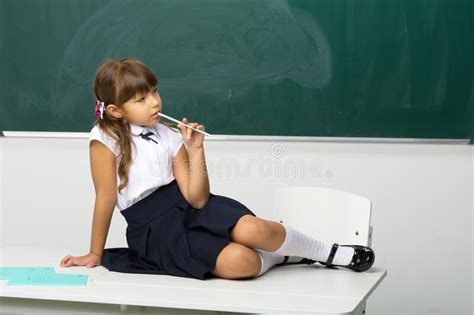 frohe schulmädchen das auf schreibtisch im klassenzimmer sitzt stockbild bild von schule