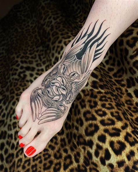 A Womans Foot With A Dragon Tattoo On It And Red Nail Polishes