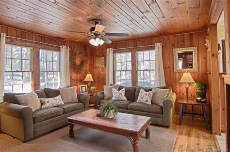 A Living Room With Wood Paneling And Couches Coffee Table Lamps And