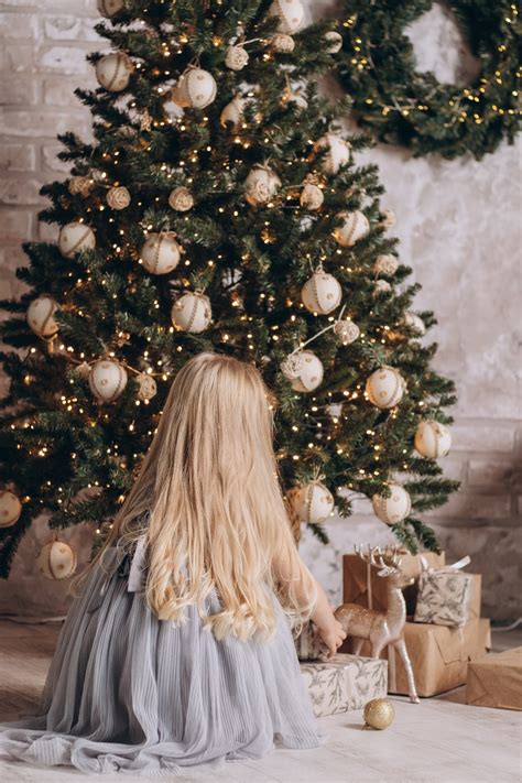 Une Petite Fille Assise Devant Un Sapin De Noël Photo Photo Sapin De