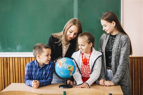 Estudiante is someone who studies something, most often in an educational institution, but not always. Estudiantes y maestro de escuela mirando mundo | Foto Gratis