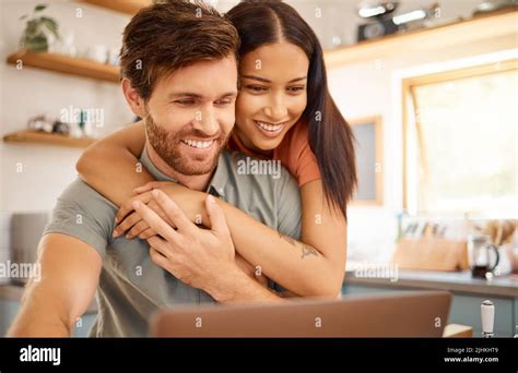 Young Happy Interracial Couple Bonding While Using A Laptop Together At