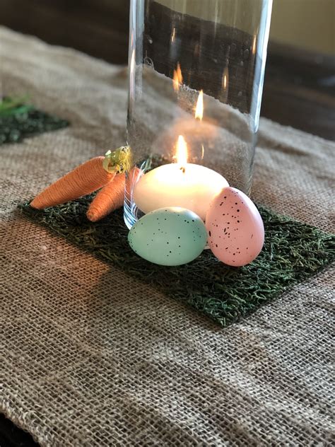 A Candle Is Sitting On A Table With Some Eggs And Carrots