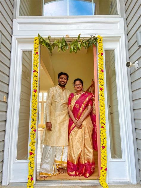 A Man And Woman Standing In Front Of A Doorway With Flowers On The Door