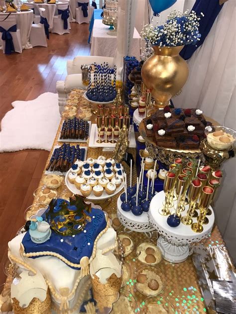 A Table Topped With Lots Of Desserts And Cake Covered In Blue And Gold