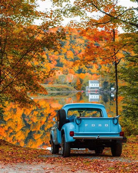 An Old Blue Truck Parked On The Side Of A Road Next To Trees With