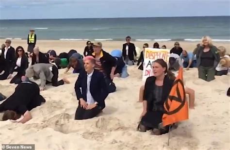 Climate Activists Bury Their Heads In The Sand At A Popular Beach In