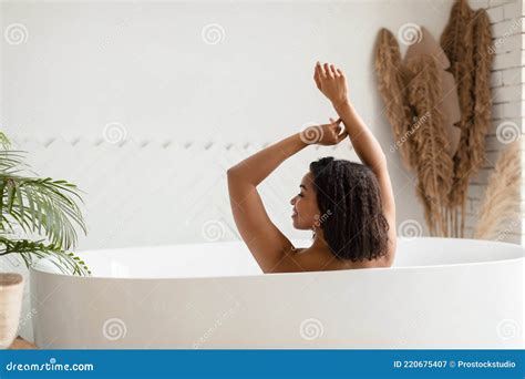 Rear View Of African American Woman Taking Bath In Bathroom Stock Image