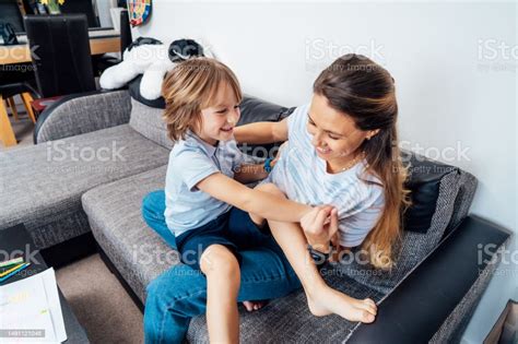 기뻐서 웃는 아이는 집에서 엄마와 즐거운 시간을 보내고 행복한 소년을 웃고 재미있는 활동적인 게임을 하고 간지럽히고 거실의 아늑한 소파에 앉아 있다 가족이 함께 휴식을