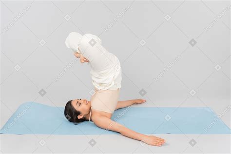 Фото Молодая индийская женщина лежа на голове на коврик для йоги