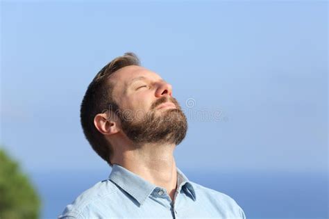 Man Breathing Deep Fresh Air Outdoors With A Blue Sky In The