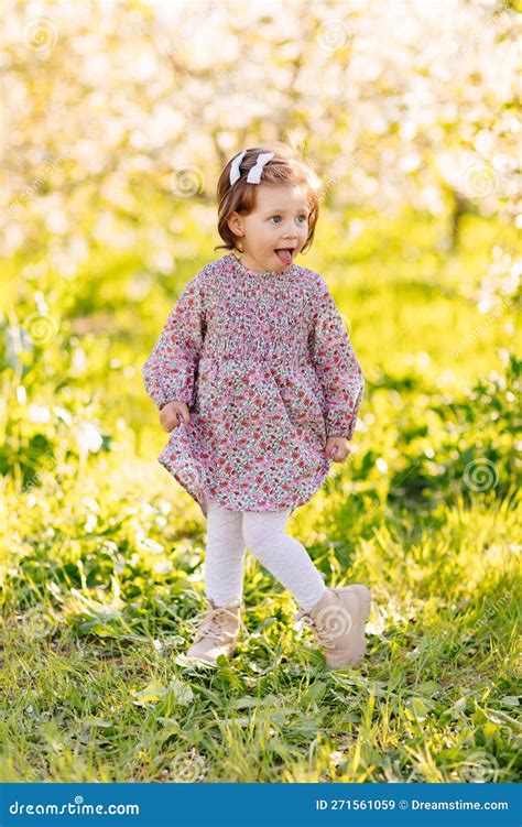 A Cute Kid Girl In A Violet Dress In A Spring Garden Stock Image