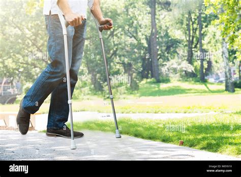 Close Up Of Man Walking With Crutches In Park Stock Photo Alamy