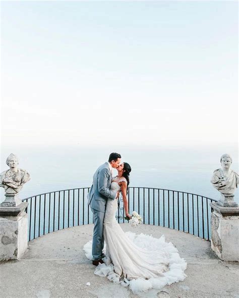 A Bride And Groom Kissing In Front Of The Ocean