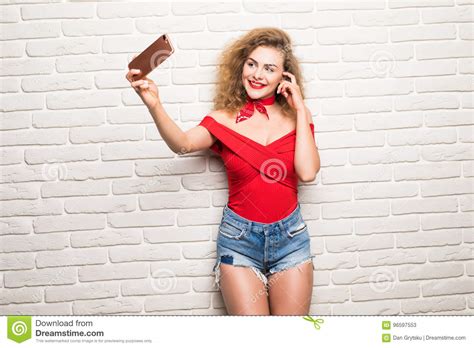 Belle Jeune Femme Faisant Lautoportrait Sur Un Smartphone Sur Un Fond De Mur De Briques Image