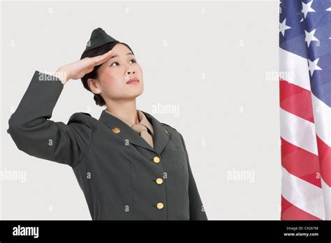 Serious Female Us Military Officer Saluting American Flag Over Gray