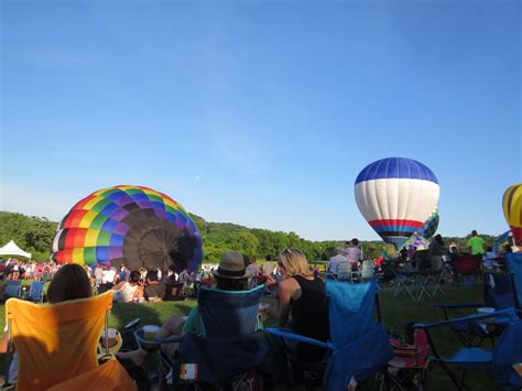 people sitting in lawn chairs watching hot air balloons being flown at