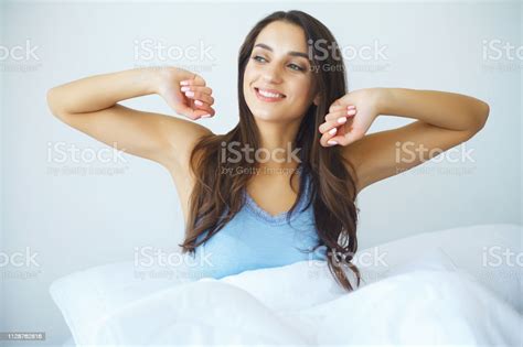 Beautiful Woman Has Woken Up And Is Sitting On A White Bed Stock Photo