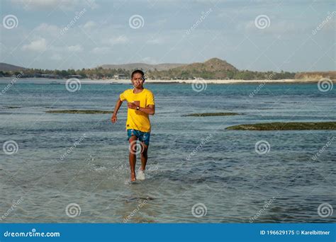 Un Hombre Negro Sano Y Atlético Sin Topless Corriendo a Lo Largo De La Playa Salpicando Agua