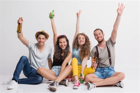 Portrait Of Joyful Young Group Of Friends With Bottles Sitting On The