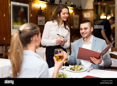 Belle Serveuse Prendre Une Commande De Deux Jeunes Amoureux Dans Un Restaurant à La Mode Photo