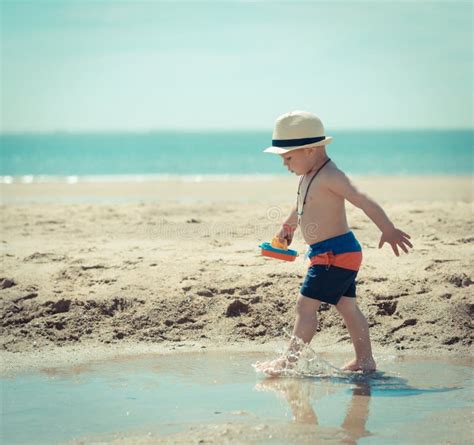 Bambino Del Ragazzino Che Cammina Sulla Spiaggia Che Ispeziona Le Coperture Fotografia Stock