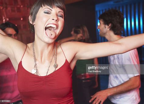 Woman In Nightclub Sticking Her Tongue Out With People Dancing Behind Her Smiling High Res Stock