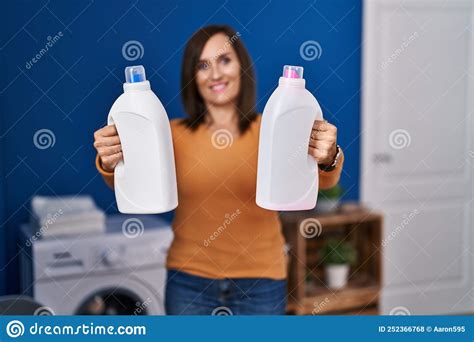 Middle Age Woman Smiling Confident Holding Bottles Of Detergent At