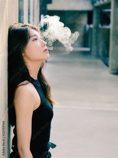 Portrait Of Beautiful Chinese Girl Smoking Outdoor And Thinking About Problems Seems A Little