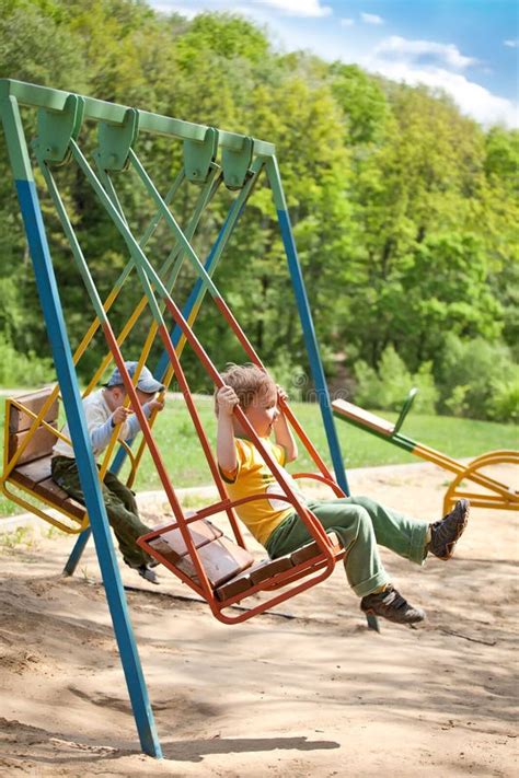 Two Boy Swinging On A Swing In The Park Stock Photo Image Of Cheerful