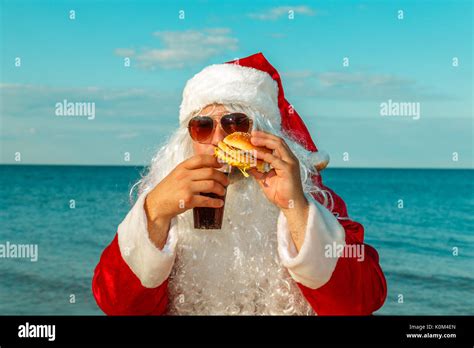 Santa Claus On The Beach Eating A Hamburger The Concept Of Unhealthy