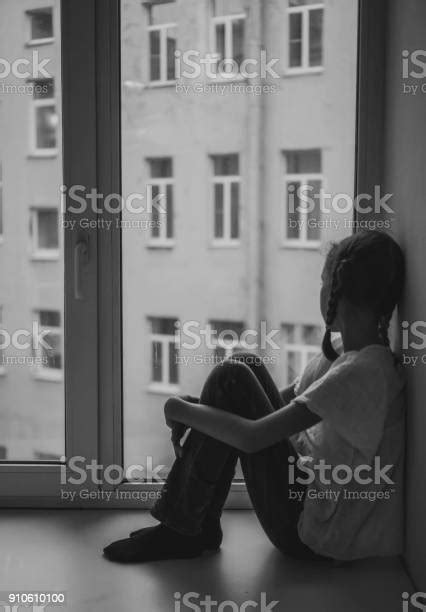 Sad Little Girl Sitting Near The Window Black And White Stock Photo