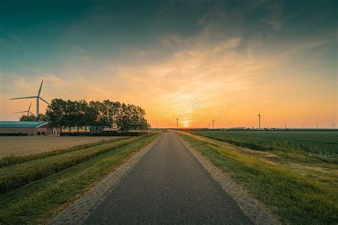 Beautiful Shot Of A Road Next To Electric Windmills During Sunset Stock
