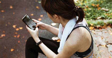 Woman Using Smartphone While Sitting On Sidewalk In Park · Free Stock Photo