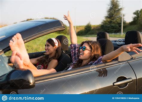Two Beautiful Young Women Driving Around In A Convertible Car Stock