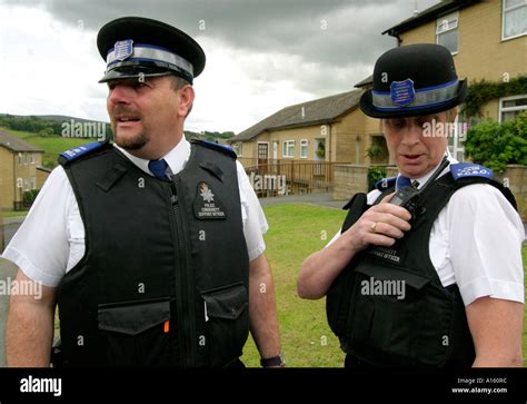 Police Community Support Officers On A Foot Patrol On A Housing Estate Using A Radio To Contact
