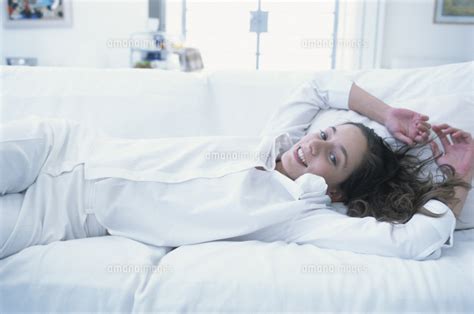 白いソファセットの上に横たわる女性 21007000554 の写真素材・イラスト素材｜アマナイメージズ