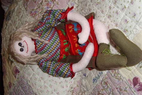 A Doll Laying On Top Of A Bed Next To A Pillow