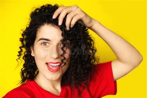 Charming Young Girl With Curly Black Hair In A Red T Shirt On A Yellow