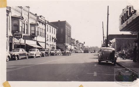 An Old Black And White Photo Of Cars Driving Down The Street